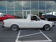 a white pick up truck parked in a parking lot next to a building with large windows