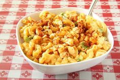 a white bowl filled with macaroni and cheese on top of a checkered table cloth