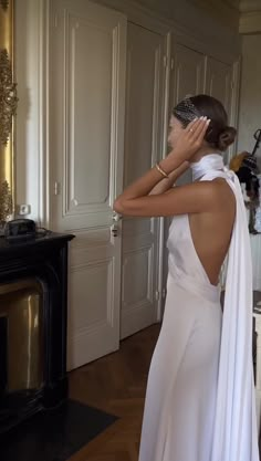 a woman in a white dress is looking at herself in the mirror with her back to the camera