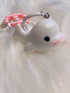 a white keychain with a dolphin on it's side and a pink ribbon around the neck