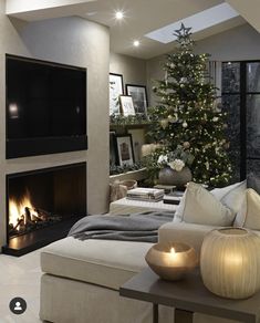 a living room with a christmas tree in the corner and candles on the coffee table