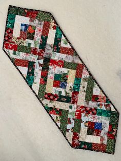 a tie that is laying on top of a white surface with red, green and blue quilts