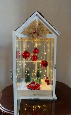 a small house with christmas decorations and lights on the inside is displayed in front of a table