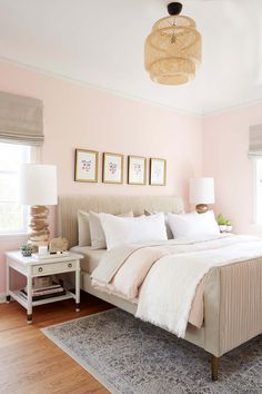 a bedroom with pink walls, white bedding and two lamps on either side of the bed