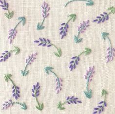 embroidered lavender flowers on white linen with green leaves and purple stems in the center,