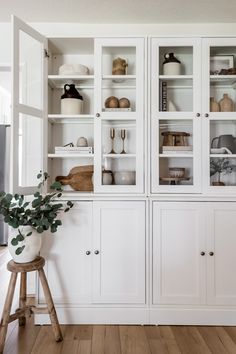 a white china cabinet with glass doors and shelves