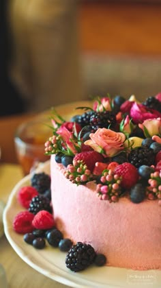 a cake with berries, raspberries and blueberries on top is sitting on a plate