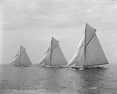 three sailboats in the ocean on a cloudy day