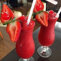 two drinks with strawberries on the rims