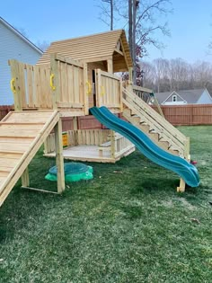 a wooden play set with a slide in the back yard