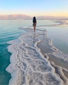 a woman walking along the edge of a body of water