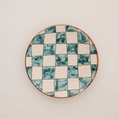 a blue and white checkerboard pattern plate on a white wall with no one around it