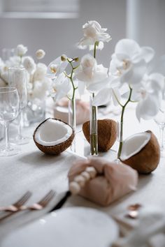 the table is set with white flowers and coconuts