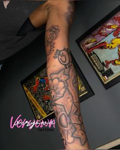 a man's arm with tattoos on it next to some other comics and posters