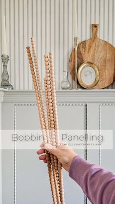 a person holding up some wooden beads in front of a shelf with other items on it