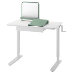 a white desk with a green book on it and a mirror above the desk top