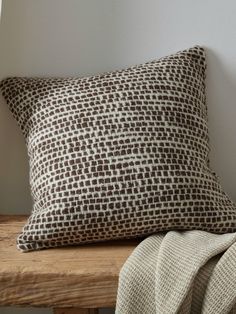 a brown and white pillow sitting on top of a wooden bench