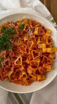 a white bowl filled with pasta and parmesan cheese on top of a table