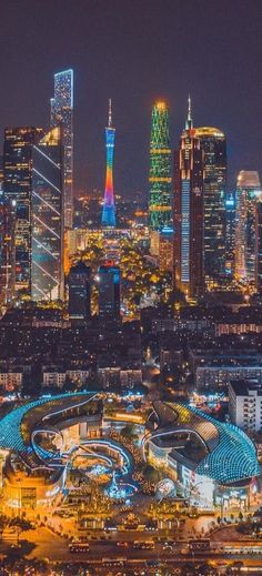 an aerial view of a city at night with lights on and buildings lit up in the background