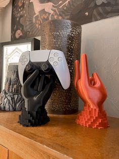 two video game controllers sitting on top of a wooden table next to pictures and sculptures