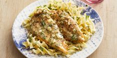 two pieces of chicken with pasta on a blue and white plate