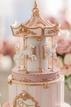 a pink and white carousel cake with gold trim