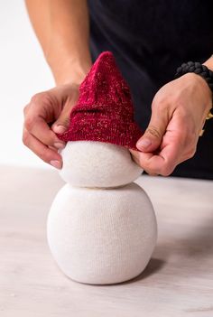 a person making a snowman out of a white ball on top of a table