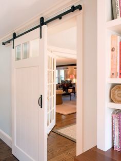 an open door leading to a living room with white walls and carpeted flooring