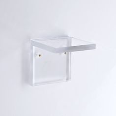 a white wall mounted glass shelf with two gold studs on the top and bottom