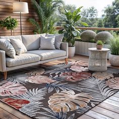 a living room area with couches and potted plants on the balcony overlooking the water