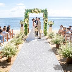 a bride and groom standing under an arch on the beach during their wedding ceremony in front of the ocean