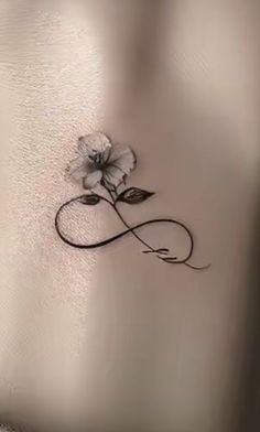 a white rose tattoo on the back of a woman's stomach, with an infinite symbol