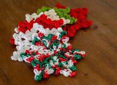 three crocheted snowflakes sitting on top of a wooden table