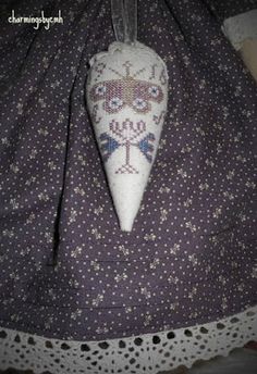 an embroidered ornament hanging from a string on a lace doily with crochet