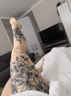 a woman with tattoos on her legs laying in bed