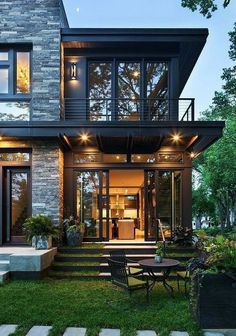 a modern house with stairs leading up to the front door and patio area, surrounded by grass