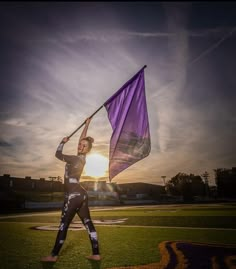 a woman holding a purple flag on top of a field