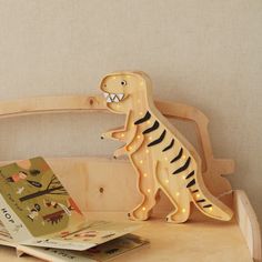 a wooden dinosaur light up toy sitting on top of a table next to a book