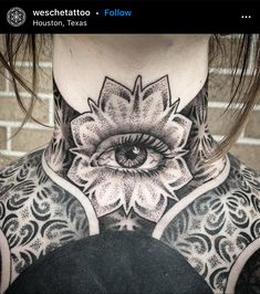 a woman's neck with an all seeing eye tattoo on her upper back piece