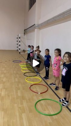 a group of young children standing in front of a line of hula hoops