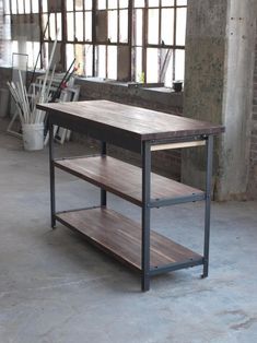 a wooden table sitting inside of a room next to a metal frame and brick wall