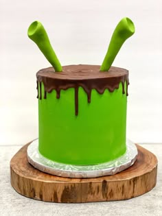 a green cake sitting on top of a wooden board covered in icing and chocolate