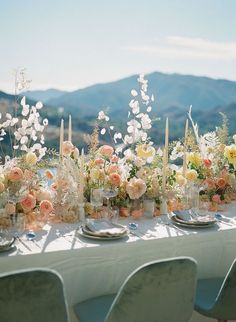 a table with flowers and candles is set up for a wedding reception in the mountains