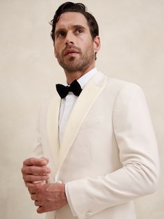 a man in a white tuxedo and black bow tie