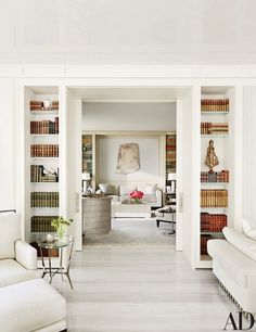 a living room filled with white furniture and bookshelves