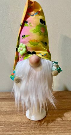 a small white gnome figurine wearing a colorful hat on top of a wooden table