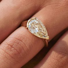 a woman's hand with a ring on it and a pear shaped diamond in the middle