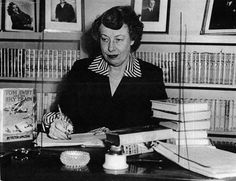 a woman sitting at a desk with books in front of her