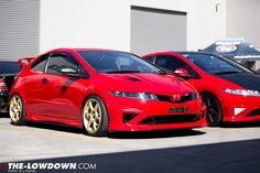 two red cars parked next to each other in front of a building with garage doors