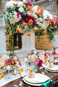 an arrangement of flowers and greenery decorates the centerpiece on this long table